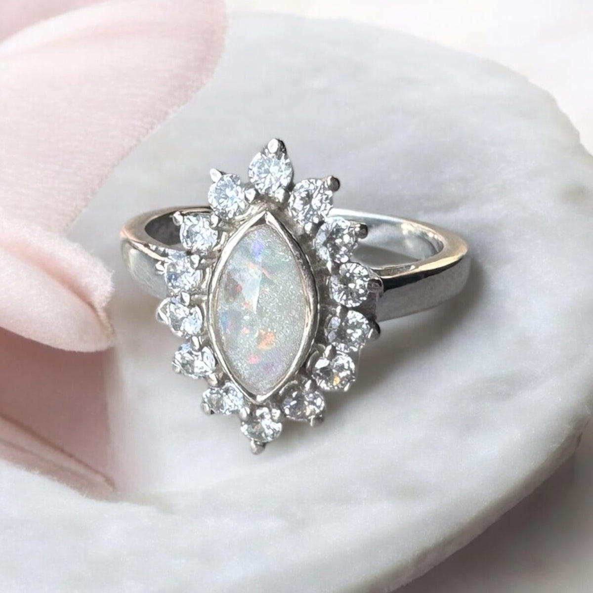 Sterling silver halo marquise ring with a breastmilk resin centre containing iridescent opal flakes.