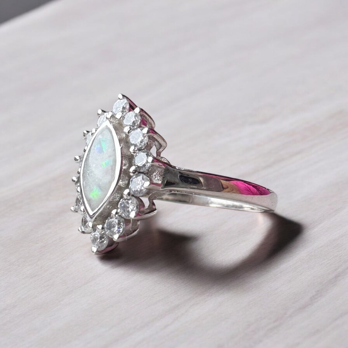 Side view of a sterling silver halo marquise ring showing its raised stone setting and polished band.