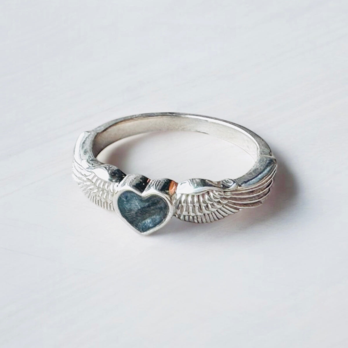 Sterling silver angel wings memorial keepsake ring, personalised with cremation ashes, breastmilk, umbilical cord, hair or pet fur. A meaningful design symbolising love, remembrance and protection. Handcrafted in West Wales by Afallon DNA Jewellery.