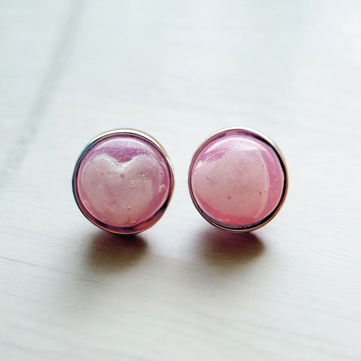 Pair of sterling silver 8mm stud earrings with pale pink hearts made from breastmilk  set inside translucent pink resin.