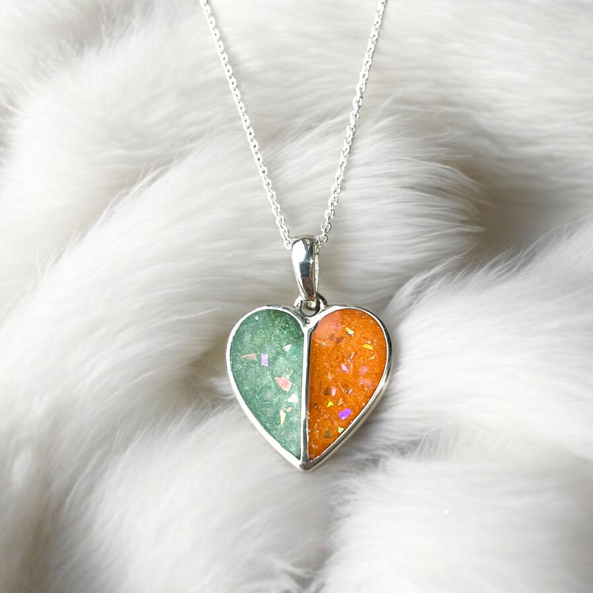 Sterling silver split heart pendant necklace with green and orange breastmilk resin sections featuring iridescent flakes.