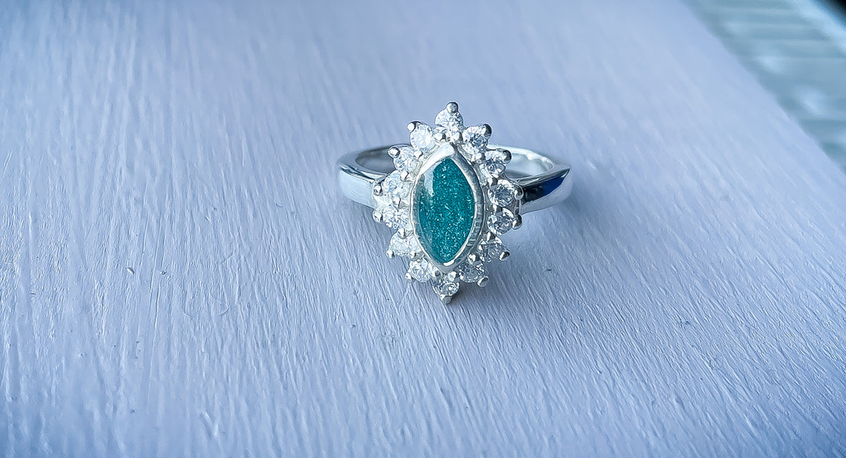 Sterling silver halo marquise ring with a deep teal resin centre surrounded by sparkling cubic zirconia stones.